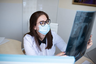 Portrait of woman working. medical mask. doctor is looking on x-ray