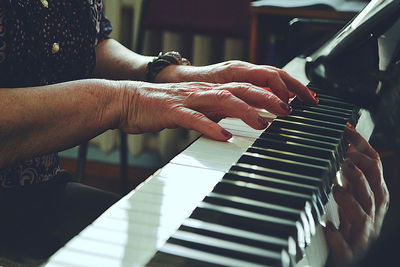 Cropped hands of woman playing piano