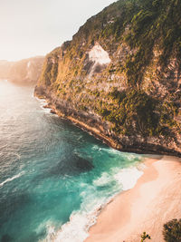 Scenic view of sea by mountain during sunset