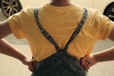 Rear view of boy standing with hand on hip