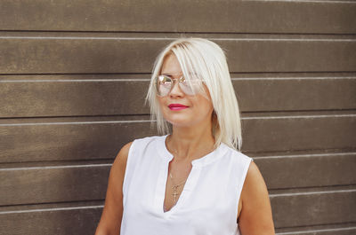 Portrait of blonde in sunglasses on background of brown blinds shutters garage house