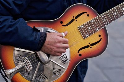 Midsection of man playing guitar