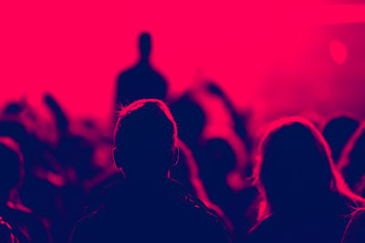 Low angle view of silhouette man standing against illuminated light