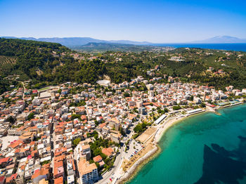 High angle view of townscape by sea against blue sky