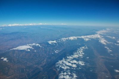 Aerial view of snowcapped mountains against blue sky