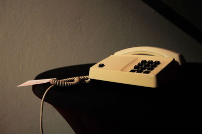 Close-up of telephone booth on table against wall