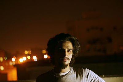 Portrait of young man in illuminated city at night