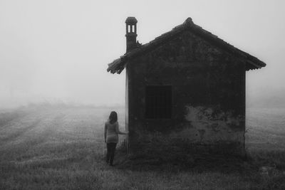 Rear view of woman standing on field against sky