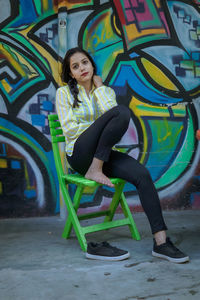 Portrait of smiling young woman against graffiti wall