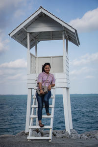 Full length portrait of teenage girl standing at sea shore against sky