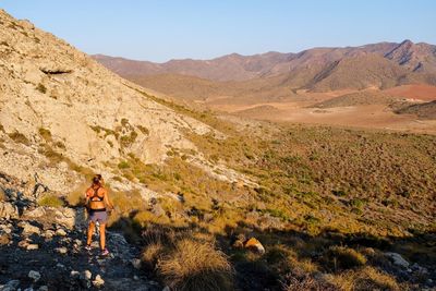 Woman standing on mountain road against sky