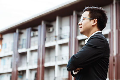 Side view of man looking away against building