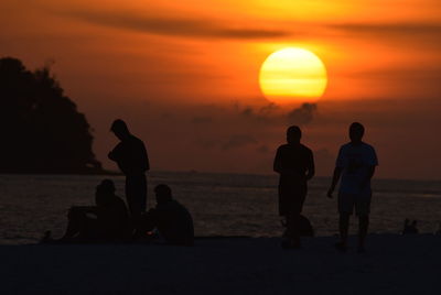 Silhouette people on beach during sunset