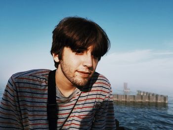 Portrait of young man looking away against sky