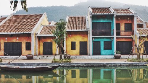 Houses by lake against buildings