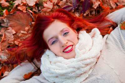 Portrait of smiling redhead young woman lying down autumn leaves