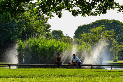 Man sitting by plants against lake