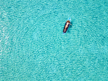 High angle view of woman lying on surfboard in swimming in pool