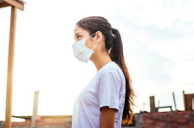 Portrait of young woman standing against sky