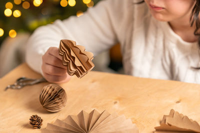 Girl makes christmas tree decorations out of paper with her own hands. step-by-step instruction