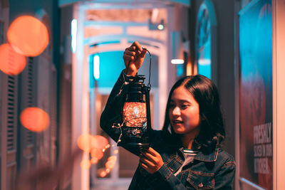 Portrait of woman holding illuminated lighting equipment