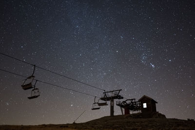 Low angle view of ski lift against sky at night