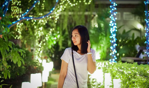 Portrait of young woman standing against trees