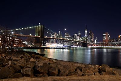 Illuminated brooklyn bridge over river at night