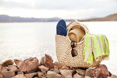 Close-up of hat on rock at beach against sky