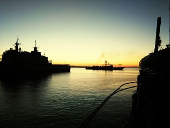 Silhouette boats in sea against sky during sunset