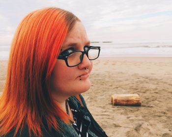 Portrait of young woman at beach against sky