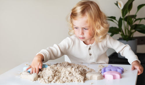 Portrait of girl playing with kinetic sand at home 