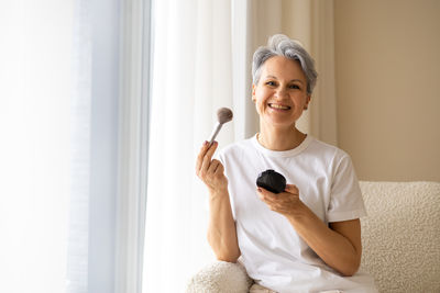 Portrait of young woman holding hands while sitting at home