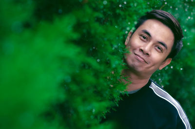 Asian man smiling with happy face standing in green bush for good mental health concept.