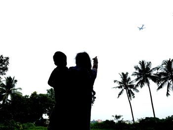 Rear view of man and woman standing against clear sky