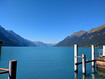 Wooden posts in lake against clear blue sky