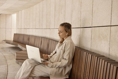 Woman using laptop while sitting on bench