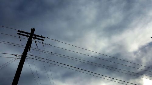 Low angle view of power lines against cloudy sky