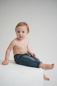 Portrait of cute baby boy sitting on bed at home