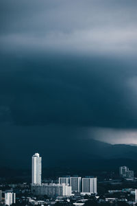 Buildings in city against storm clouds