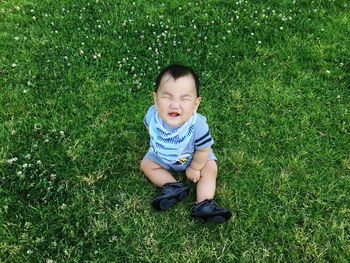 High angle view of cute baby boy sitting on grassy field