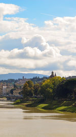 Scenic view of river by buildings against sky