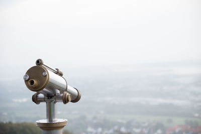 Close-up of hand-held telescope against cityscape during foggy weather