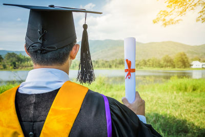 Rear view of man in graduation gown standing outdoors