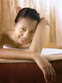 Close-up portrait of young woman lying on bed