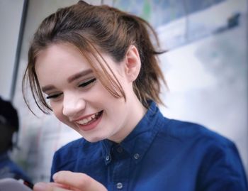 Close-up of smiling young woman using mobile phone at home