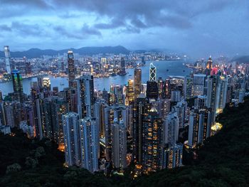 High angle view of illuminated city by sea against sky