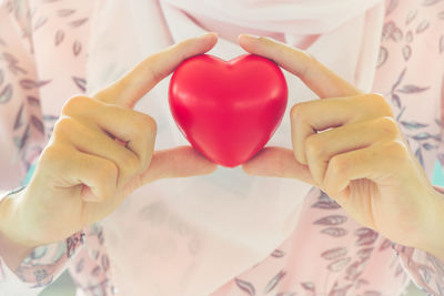 Midsection of woman holding heart shape