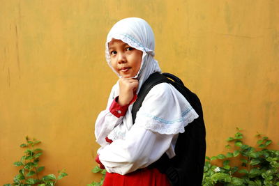 Portrait of smiling girl standing against wall