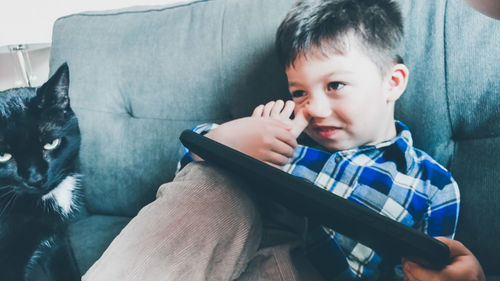 Boy looking away while sitting on sofa at home